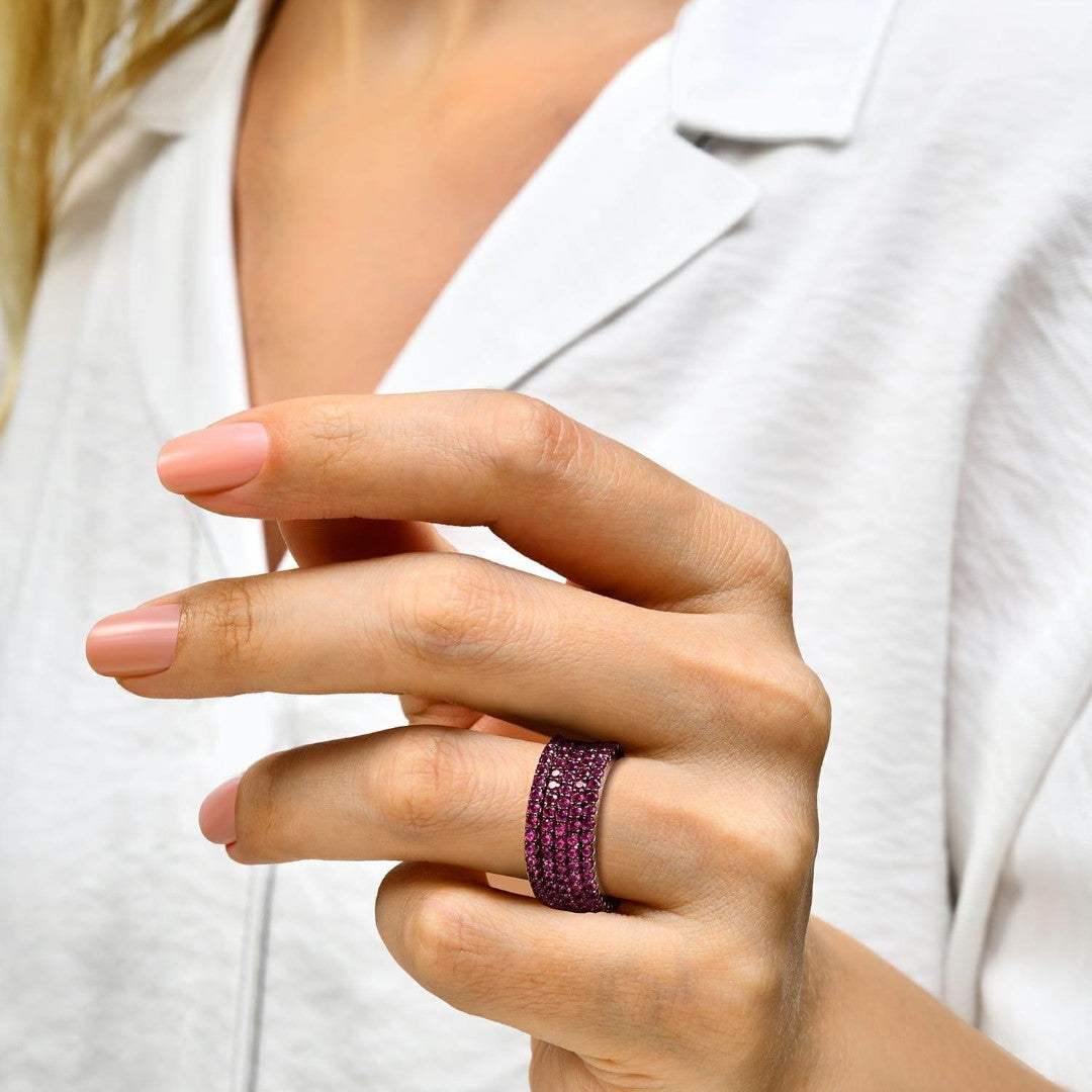 Sterling silver rhodium-plated ring with purple ruby stones worn on hand.